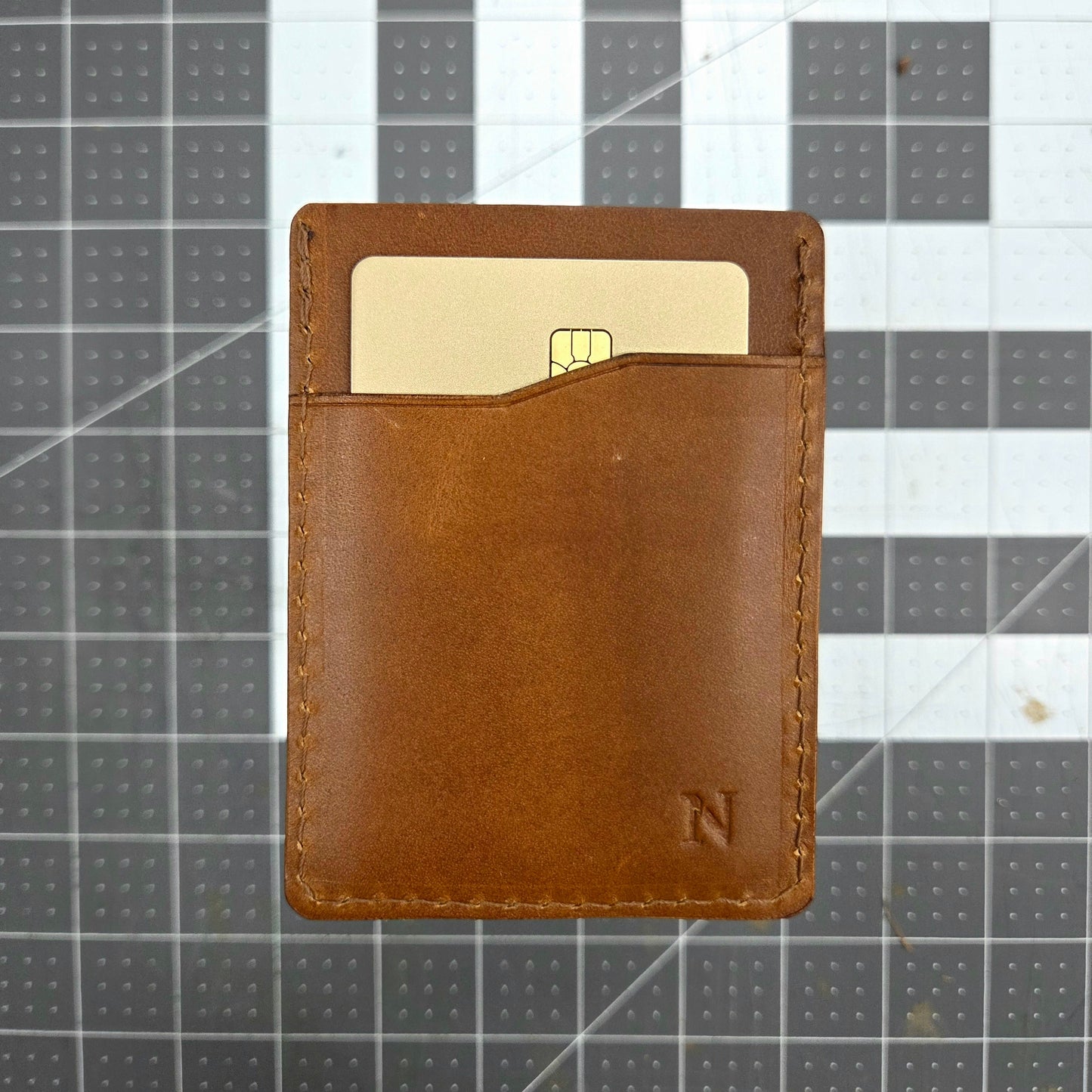 Brown leather wallet with a card on a grid background